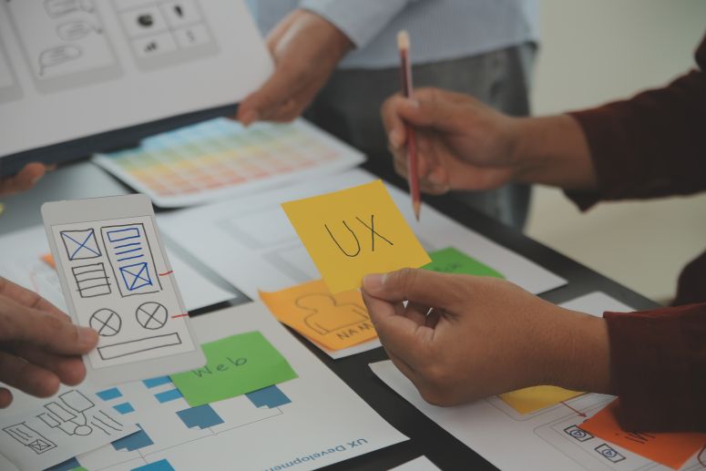 Uma mesa com várias anotações, em destaque um post it escrito UX.