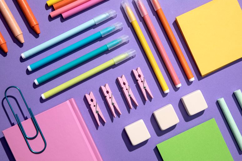 A imagem mostra Itens de papelaria sob fundo roxo