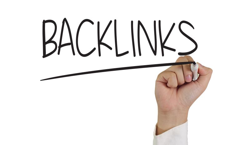 Uma mão escrevendo a palavra backlinks em uma lousa transparente.