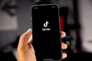 como recuperar conta do TikTok: Mãos com o app no celular