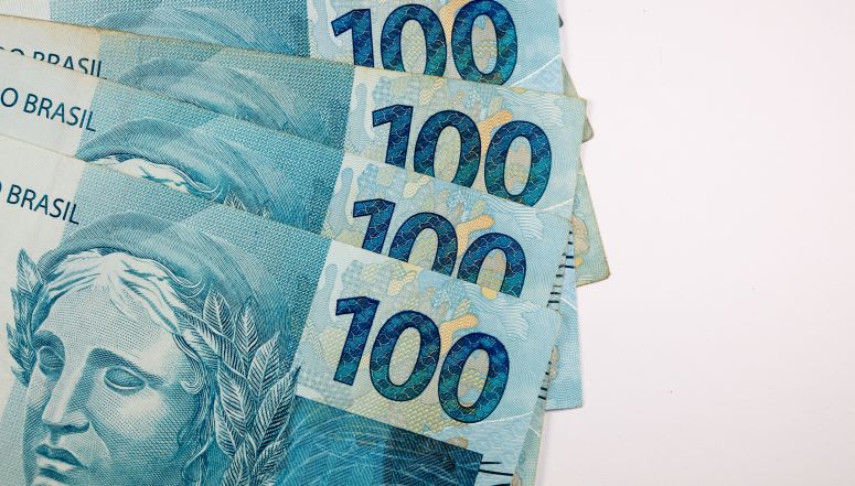 a imagem mostra um punhado de notas de R$ 100,00.