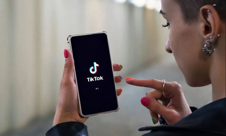 Biografia do TikTok - Jovem com celular na mão usando app TikTok