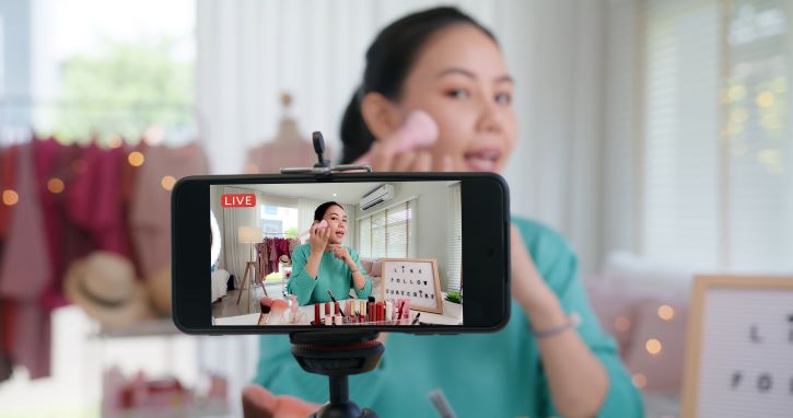 Mulher asiática micro influenciadora grava câmera de vídeo viral ao vivo em estúdio doméstico. Com certeza ela busca o melhor horário para postar no tiktok.