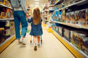 a imagem mostra uma criança e uma mulher andando pelos corredores de uma loja de brinquedos.