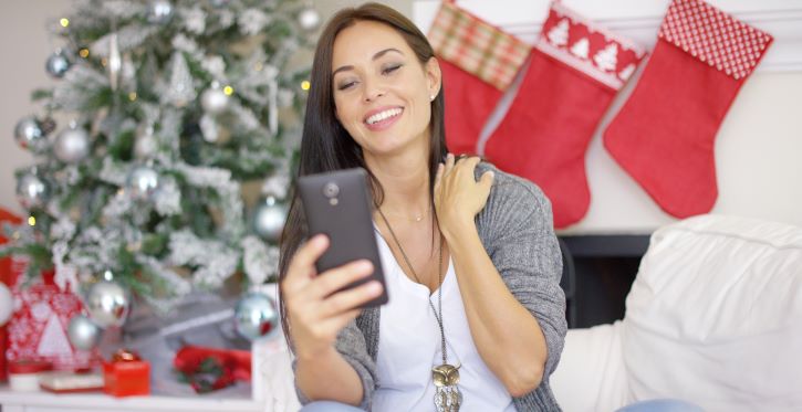 a imagem mostra uma mulher recebendo uma mensagem de natal de uma loja que ela costuma comprar