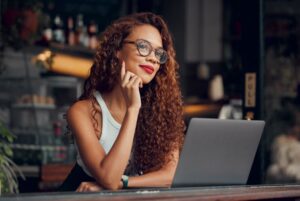 Mulher negra, trabalhando em um café em um laptop e trabalhando remotamente on-line