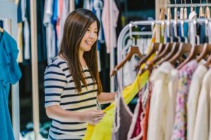 a imagem mostra uma consumidora comprando roupas em uma loja.