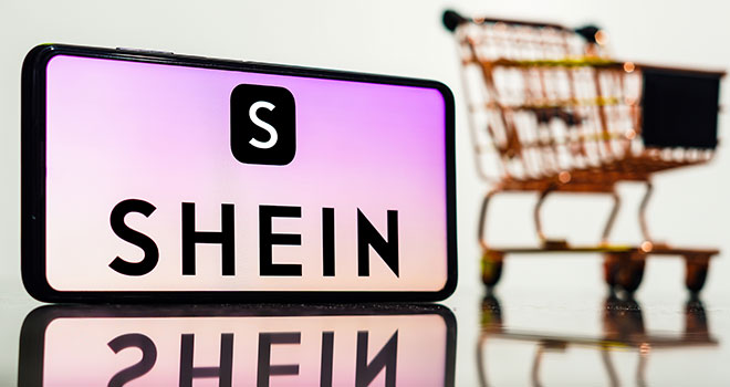 Smartphone com a logo da Shein na tela e um carrinho de compras atras