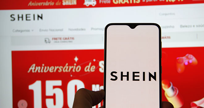 Smartphone com aplicativo shein em frente ao computador