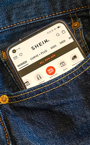 Celular com o aplicativo da Shein aberto dentro do bolso de uma calça jeans