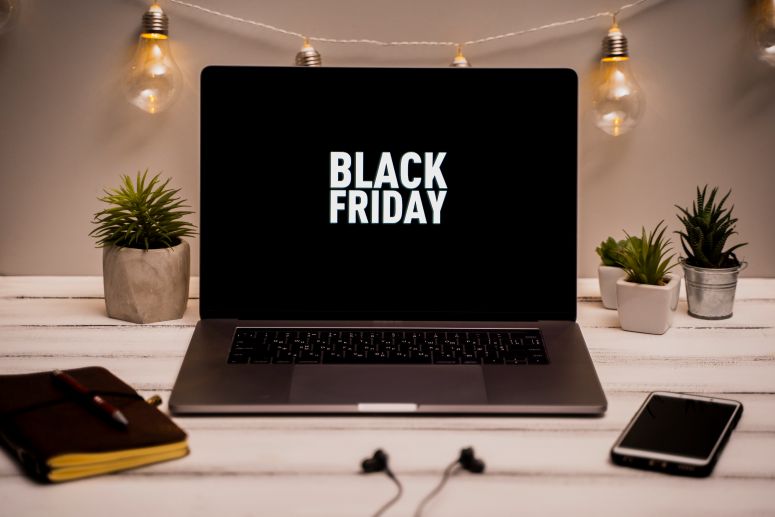 A imagem mostra a palavra Black Friday em um fundo escuro sob uma mesa decorada