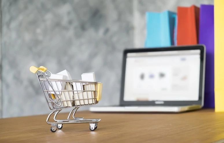 a imagem apresenta um carrinho de compras e um notebook representando o ecommerce