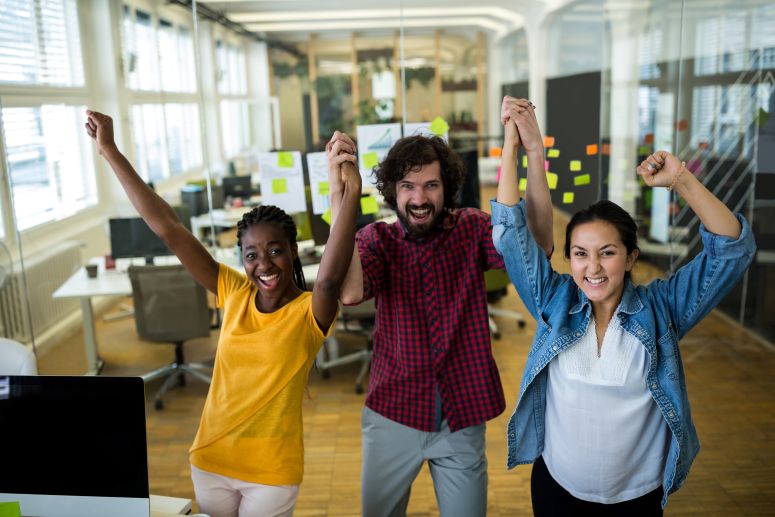 "Equipe de trabalho celebrando em um ambiente corporativo, representando a importância de missão, visão e valores alinhados para o sucesso empresarial.