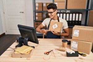 Empreendedor organizando um pacote enquanto monitora o estoque em seu sistema, representando o controle eficiente de multi estoque para e-commerce.