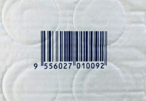 Código de barras impresso em embalagem de papel com textura, representando identificação de produto para controle de estoque e vendas.