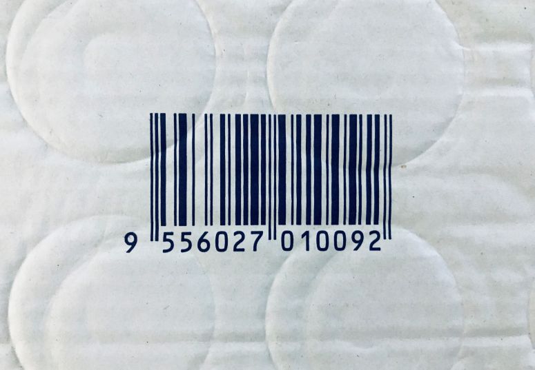 Código de barras impresso em embalagem de papel com textura, representando identificação de produto para controle de estoque e vendas.