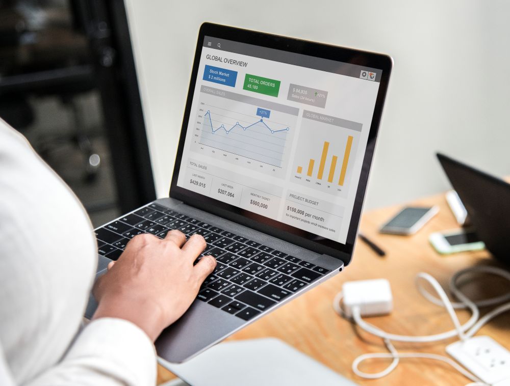 Pessoa analisando gráficos de desempenho e métricas de vendas em um notebook, representando estratégias de marketing de conteúdo e SEO para e-commerce.