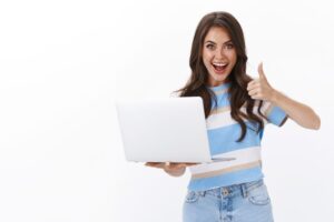 A imagem mostra uma mulher jovem feliz com notebook na mão