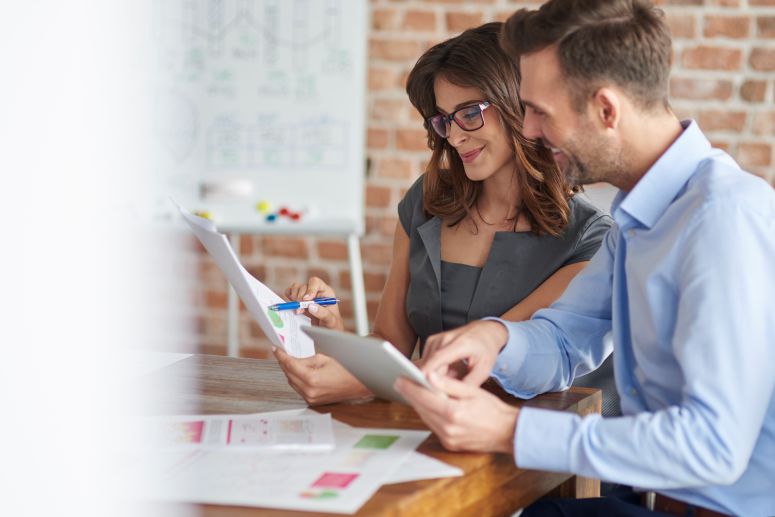 homem e mulher analisando um relatório de forma positiva.