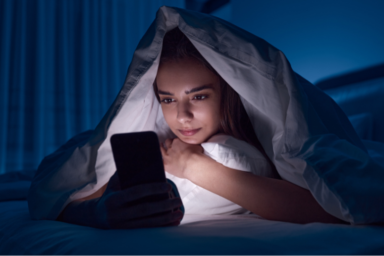 mulher jovem usando smartphone na cama