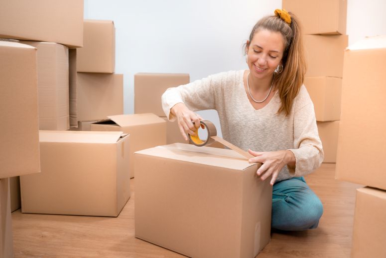 Mulher embala pacotes em Caixa de papelão 