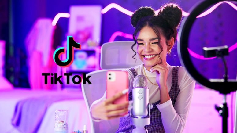 Influenciadora mostrando celular com logo do TikTok, ilustrando o uso do TikTok Shop para e-commerce