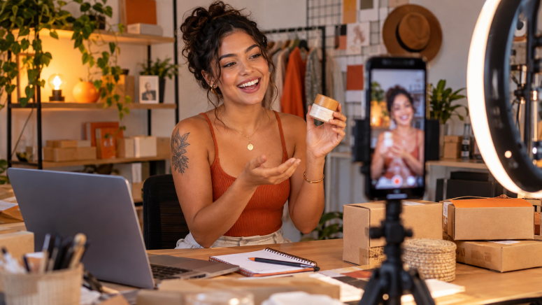 Uma mulher fazendo uma live dos seus produtos com o celular.